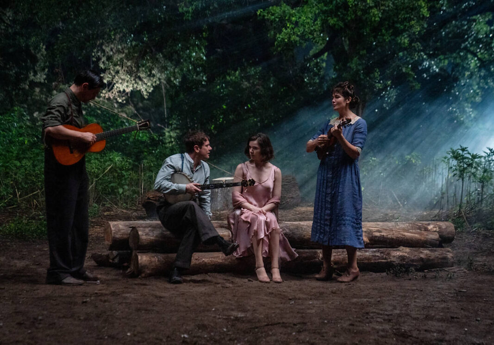 Grupo de músicos em trajes de época tocando instrumentos em floresta iluminada por feixes de luz, cena lírica do filme “Pecadores” com atmosfera sulista e nostálgica.