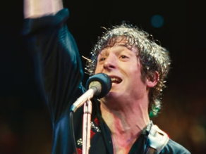 Jeremy Allen White interpretando Bruce Springsteen em performance energética no palco, com microfone à frente e expressão intensa, no filme biográfico Springsteen Salve-me do Desconhecido