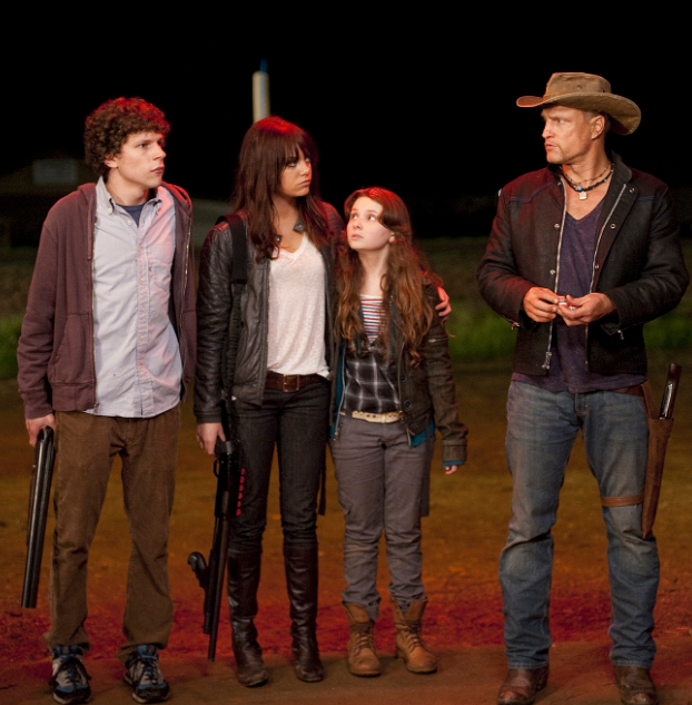 Os quatro protagonistas de Zumbilândia (2009) — Columbus, Wichita, Little Rock e Tallahassee — em pé, armados, observando algo fora da cena, iluminados por luz avermelhada.