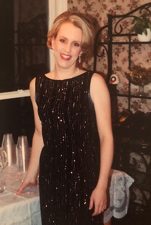 Woman standing by a table, wearing a sparkly black cocktail dress