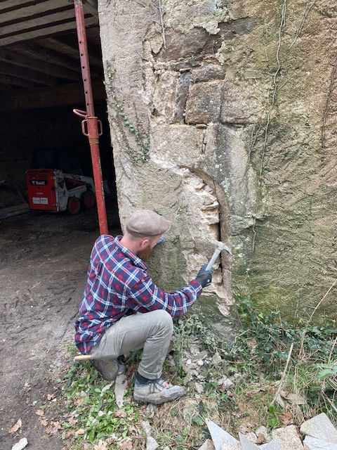 Maçon tailleur de pierre qui fait une découverte dans un mur