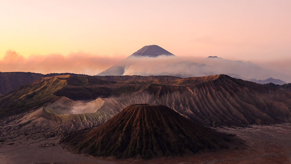 Stunning view of Mount Bromo in Indonesia at sunrise, with layers of volcanic craters, soft mist, and a vibrant sky, showcasing the dramatic landscape of East Java.