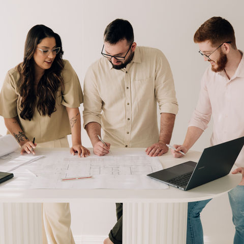 Três colegas olhando plantas em uma mesa