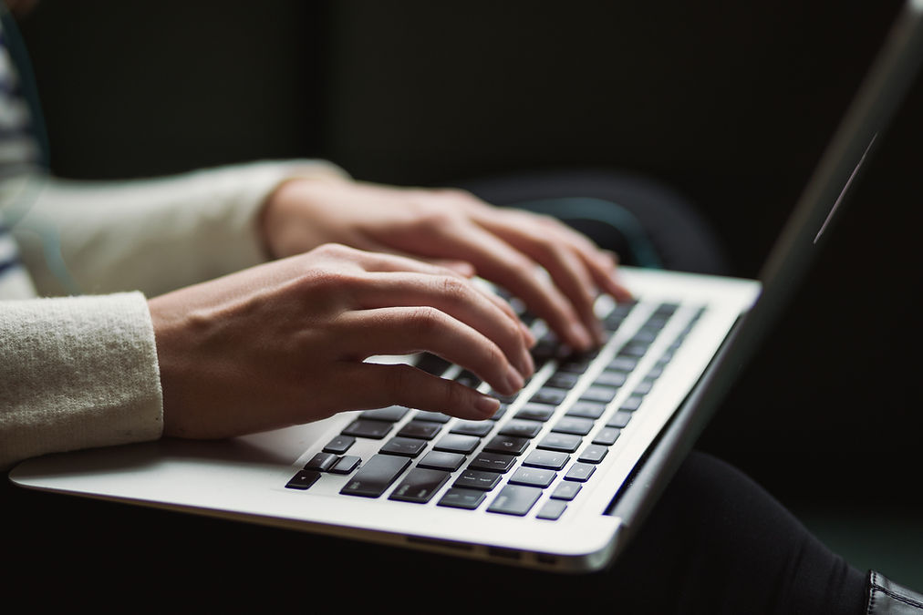 A woman's hands typing on a Macbook keyboard