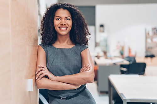 Woman leaning on wall smiling with arms crossed, expressing resilience and well-being resulting from clear boundaries.