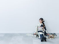 白い壁に寄りかかる振袖の女性