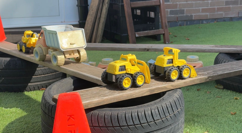 Yellow toy trucks on planks and tires