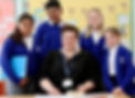 Teacher smiling with four primary students in a classroom.
