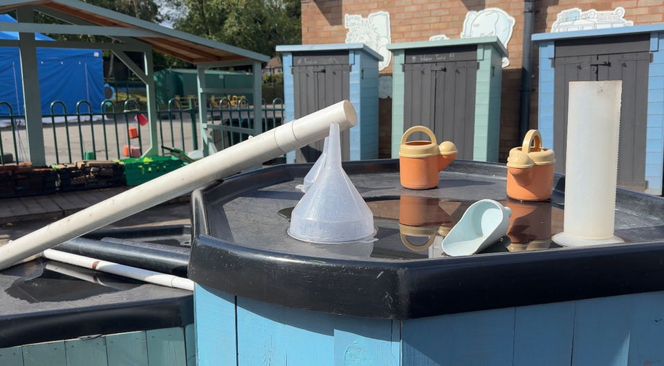 Nursery water play station with pipes, funnels, and toys