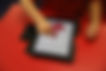 Child drawing a red shape on a tablet