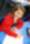 Smiling girl in red uniform writing at desk