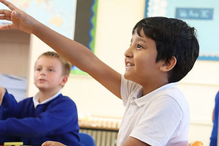 Young boy raising hand in classroom