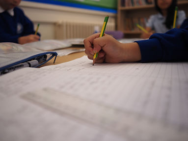 Child writing with a pencil in class