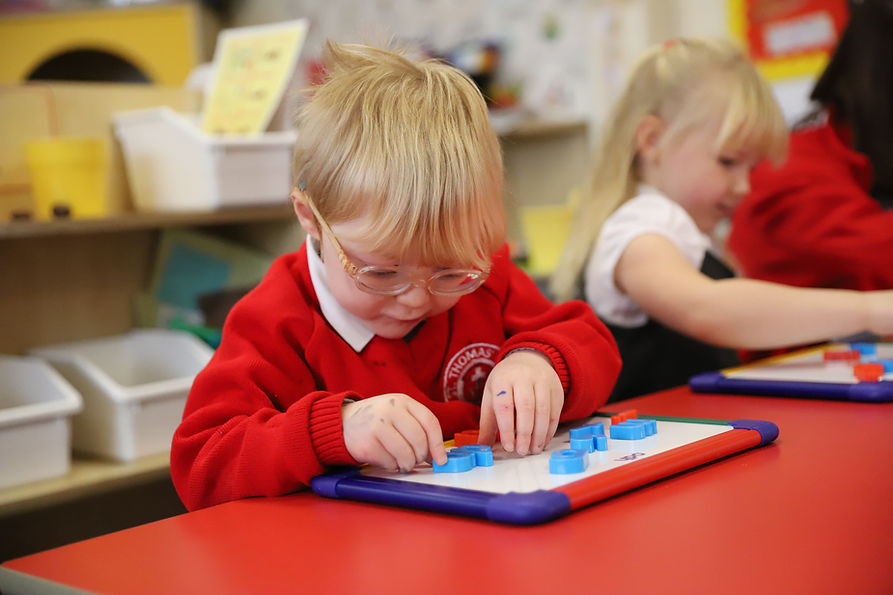 Young boy in red uniform playing with letter magnets