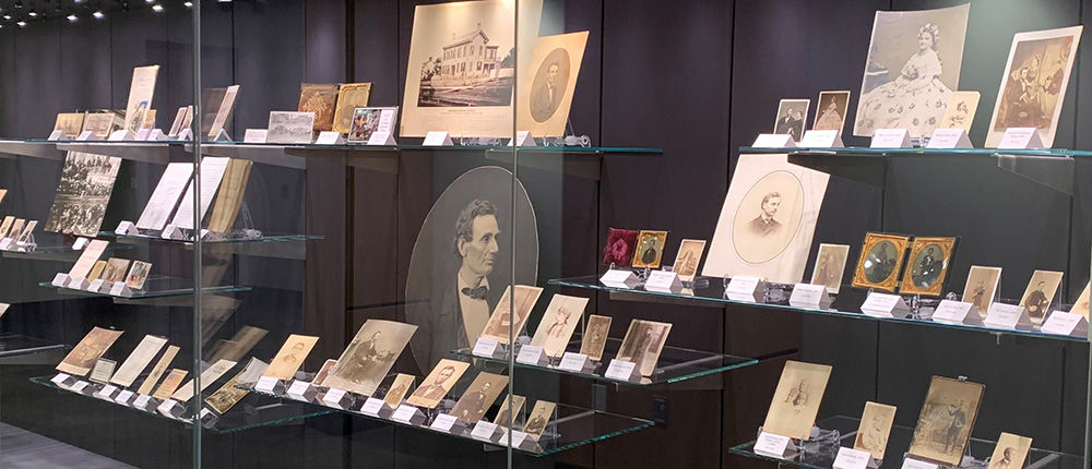 Display case featuring historical documents and portraits at The Rolland Center for Lincoln Research.