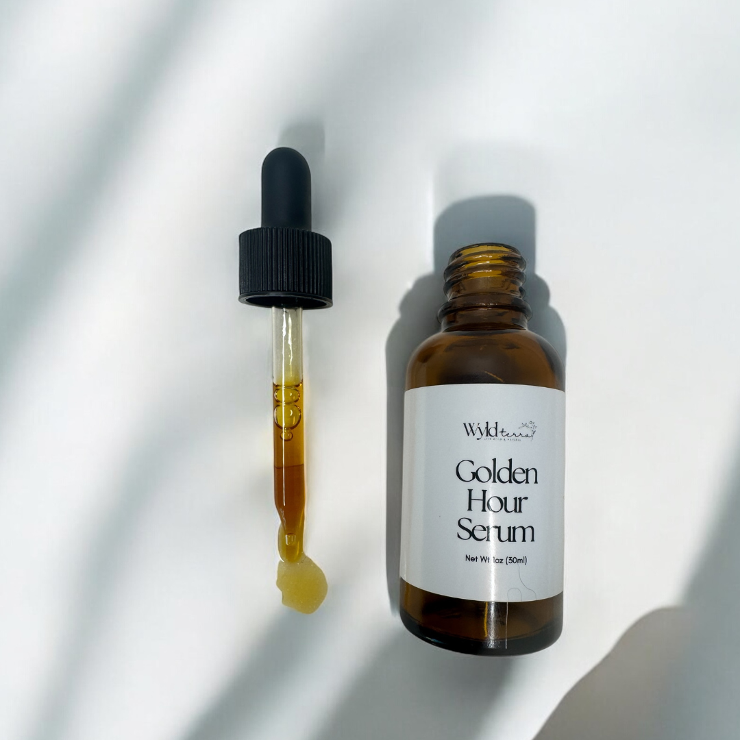 amber glass dropper bottle with the dropper laying next to it filled with face oil in it and spilling out the bottom