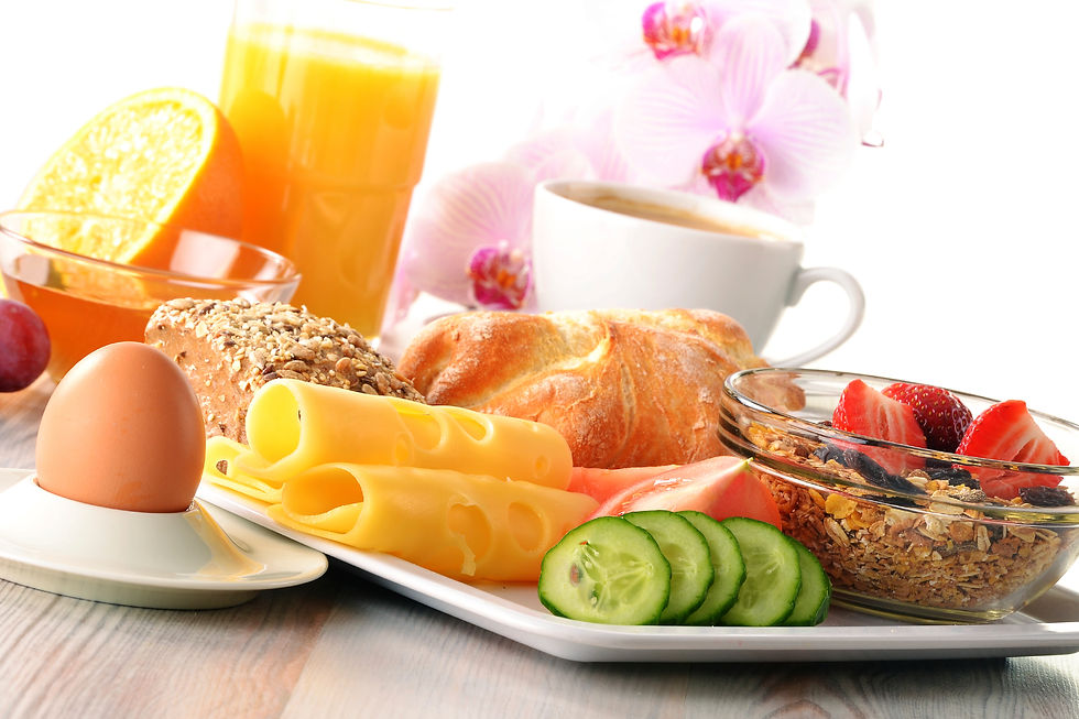 Petit-déjeuner copieux avec œuf, pain, fromage, fruits, concombre, jus d’orange et café, sur fond blanc avec orchidées.