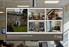 Estate agent digital window display showing properties for sale