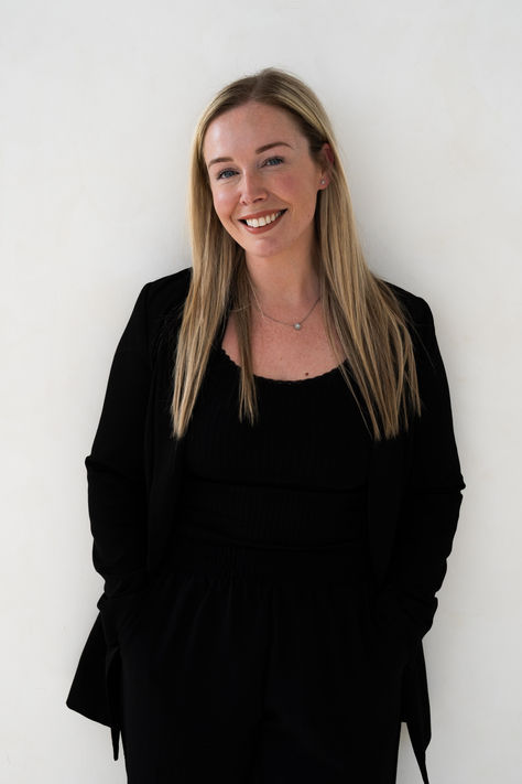 Smiling person in black outfit against white background.