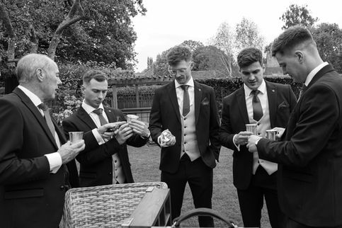 Five men in suits, holding drinks outdoors.