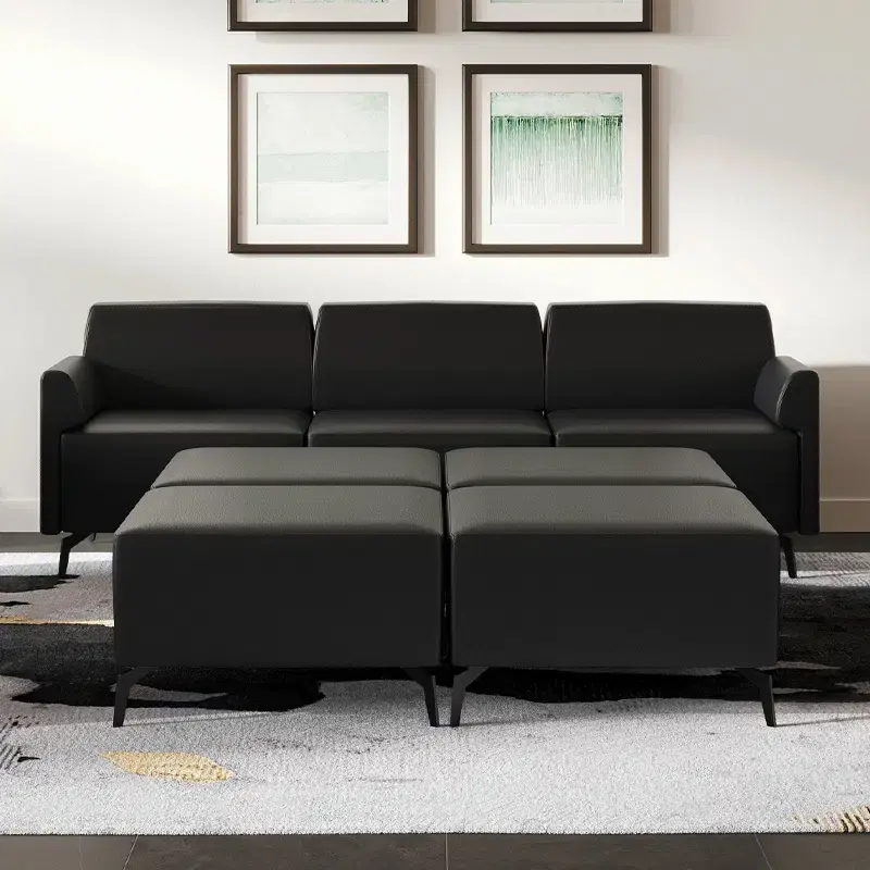 Thumbnail: Black leather couch with two ottomans in front of framed art.