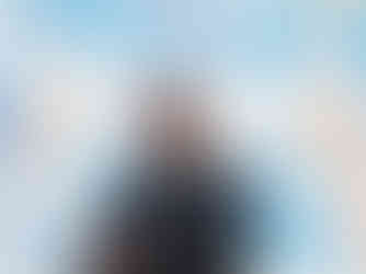 A man stands in front of a projection of a castle, smiling with his arms folded