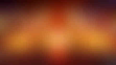 A large orange and yellow stage with a huge crowd surrounding. There are gold motifs and pyrotechnics being used