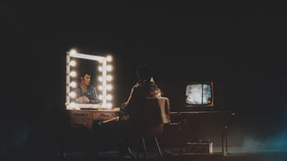 Elvis Presley sitting at a dressing room mirror, illuminated in the reflection