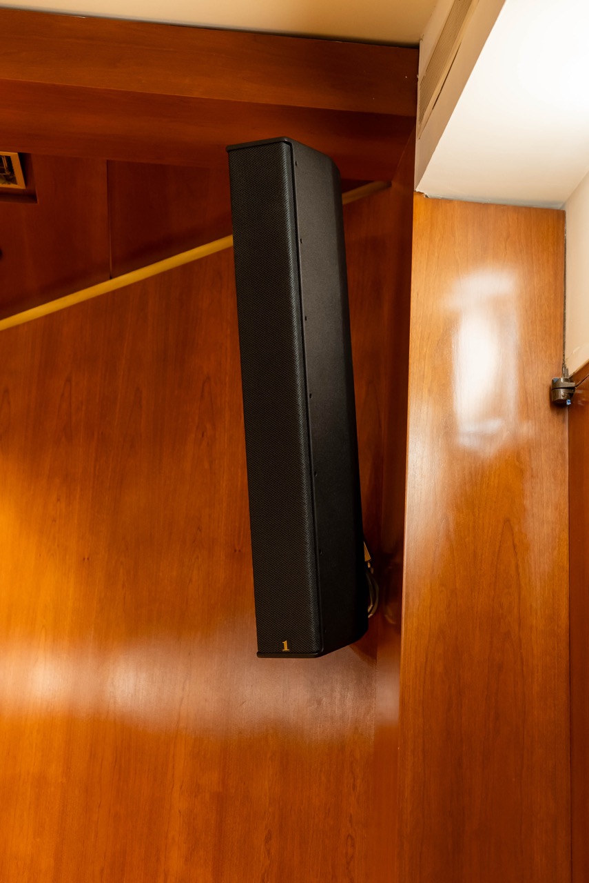 A long black speaker attached to a wooden wall