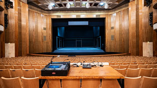 An empty auditorium with a stage and a table with microphones