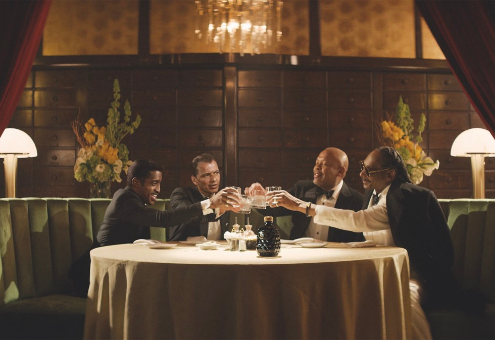 Four men sit around a round table in a restaurant. They cheers their glasses together