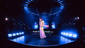 Gracie Abrams wearing a long dress and singing in the middle of a blue stage