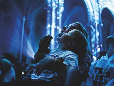 A parent and child looking up at a projection on the roof of a cathedral