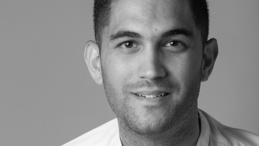 A black and white photo of a young man smiling and wearing a white shirt