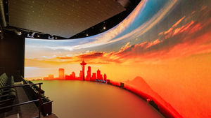 A large curved LED screen showing a cityscape in an immersive theatre