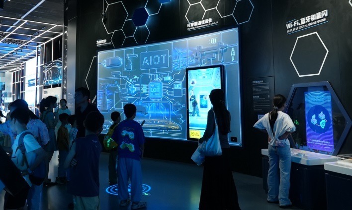 A dimly-lit exhibition in a science museum with children playing with the interactive displays on the wall