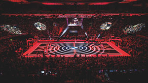 A packed basketball arena with red and black lighting
