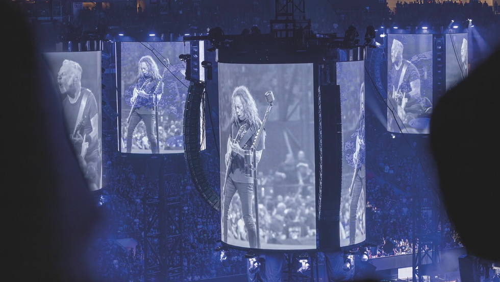 An arena with columns of LED screens showing a man playing guitar