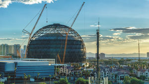 A cityscape with a large dome in the middle being built with cranes