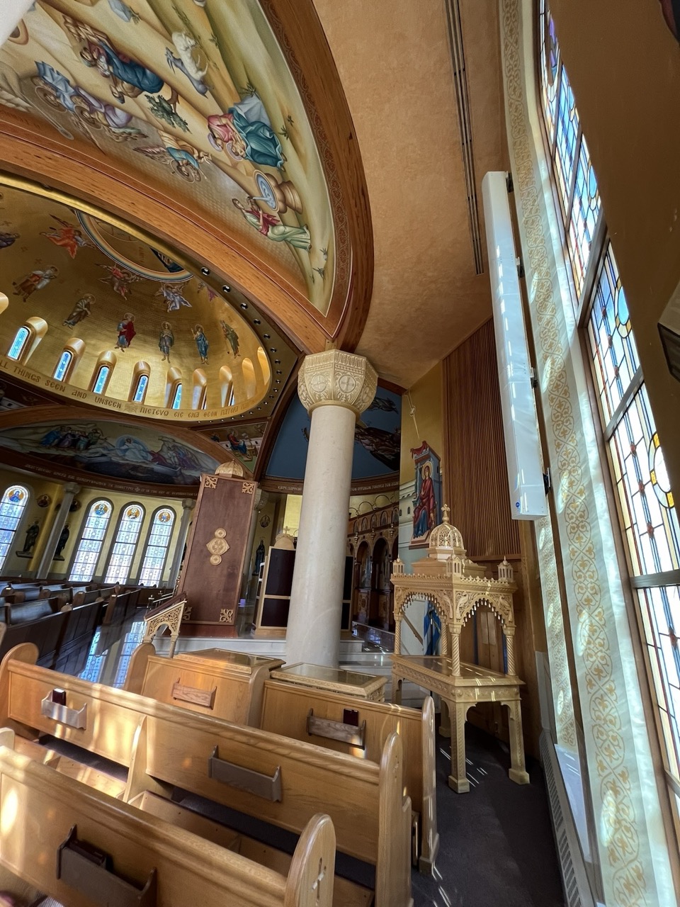 A church with a decorative roof, columns and stained glass windows. The photo shows a loudspeaker hidden discreetly on the wall