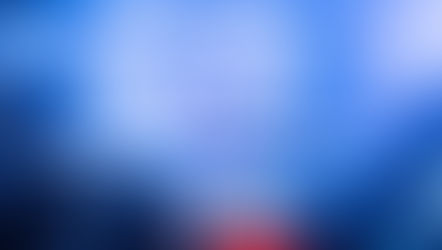 A packed concert hall with a T-shaped staged lined with dancers in pink and blue lighting