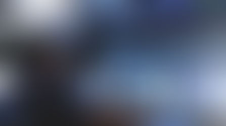 A person uses a mouse in a dark control room with multiple computers