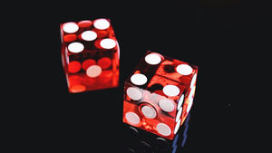 Two red die sitting on a shiny black surface
