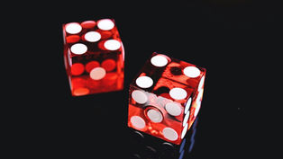 Two red die sitting on a shiny black surface