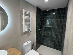 Reforma de baño con ducha a ras de suelo, azulejo verde y mueble de madera