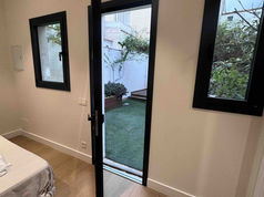 Dormitorio reformado con carpintería de aluminio negro y suelo laminado