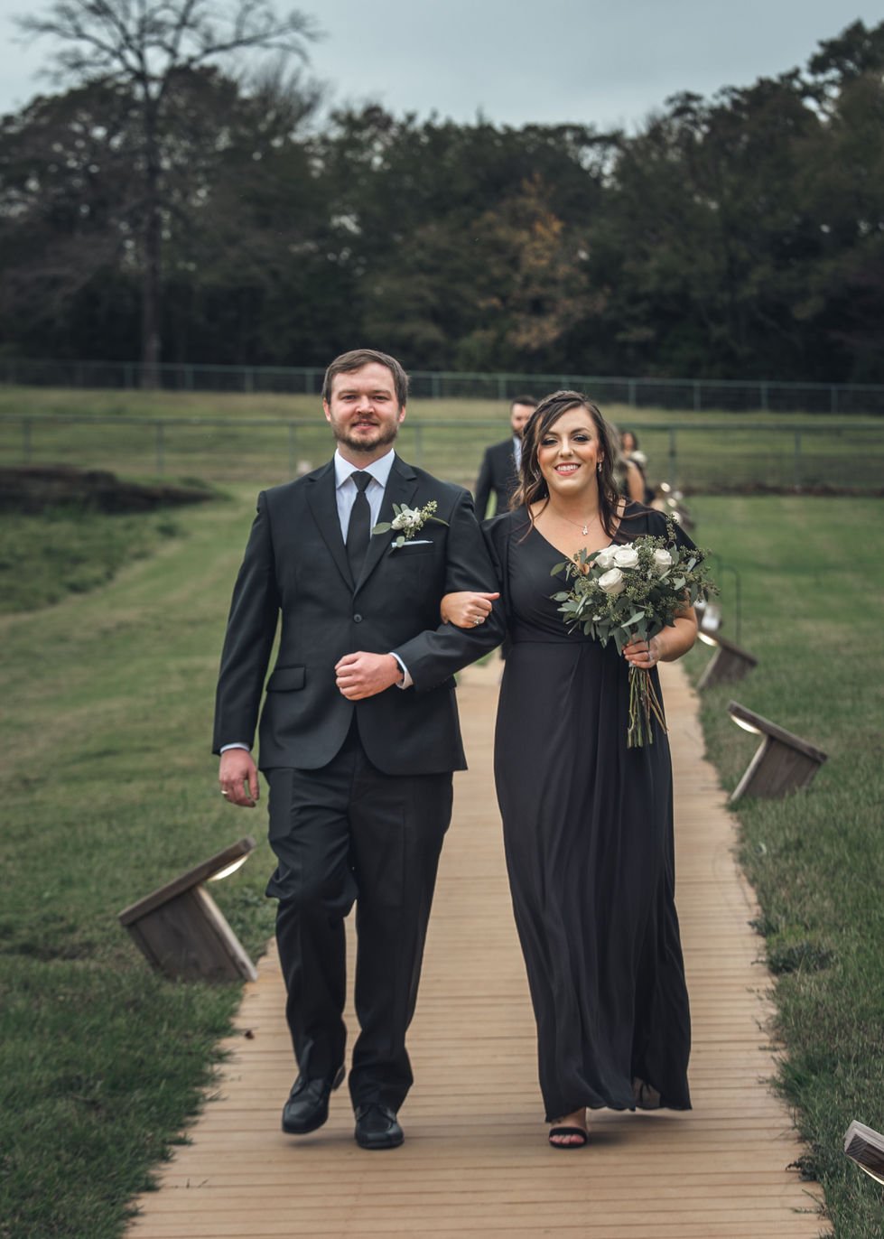 Groomsman and bridesmaid holding hands while walking the aisle