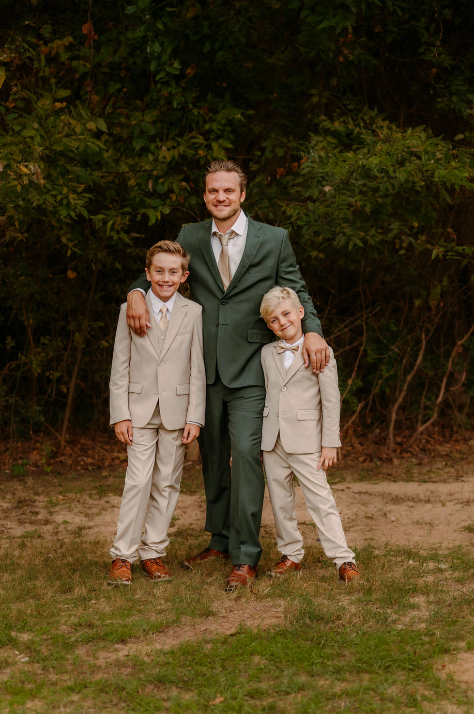 Two young boys in green suits standing outdoors at the wedding