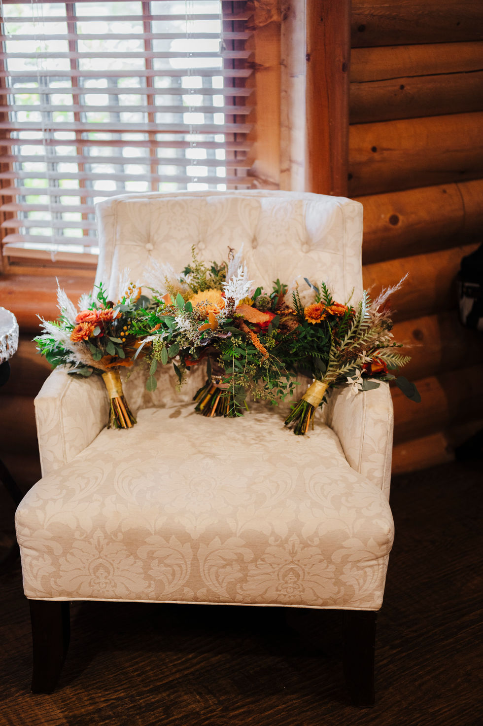 Floral arrangement on a bench beside a log cabin wall