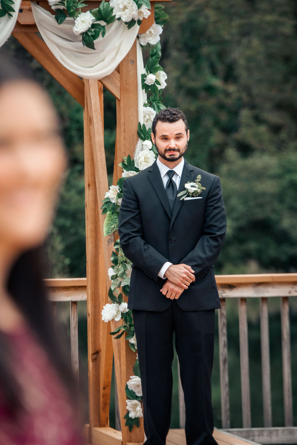 Groomsman standing at the wooden ceremony arbor